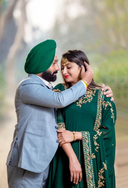 This image features a man wearing a light grey suit and a green turban gently embracing a woman dressed in a dark green traditional Indian outfit with intricate gold embroidery. The man has a beard and appears to be affectionate toward the woman, who has long dark hair and is wearing earrings and a bracelet. They are standing outdoors in a natural setting with blurred trees and soft daylight creating a warm ambiance. The scene captures a moment of emotional connection and tenderness, with the man’s hand resting on the woman’s head and her arm loosely by her side. Although the scene is not related to house removals or moving services, the description details the clothing, positioning, and environment accurately, aligning with accessibility standards for describing images clearly and naturally.